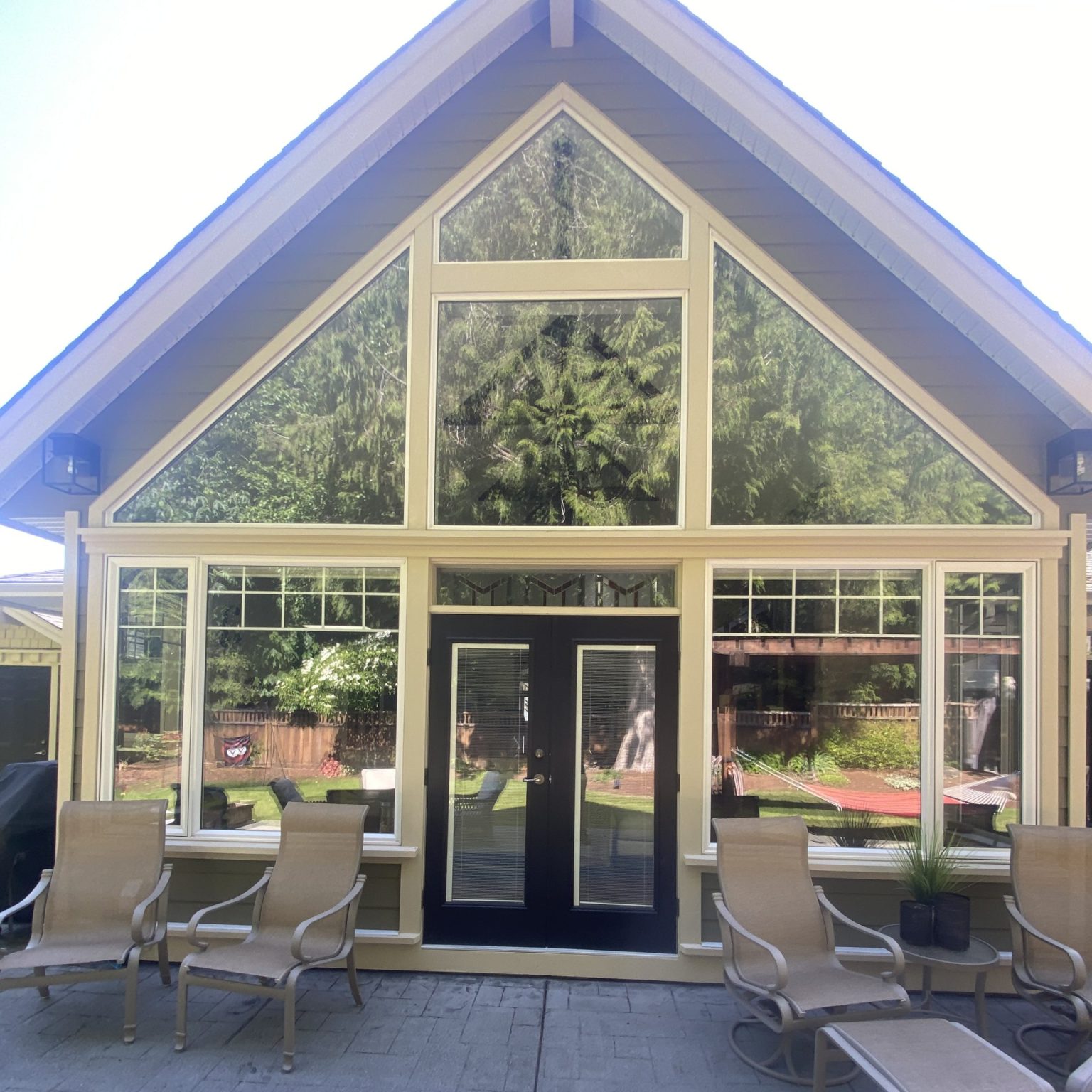 A large A-Frame home, seen from outside with expansive windows taking most of the space on the side of the house.