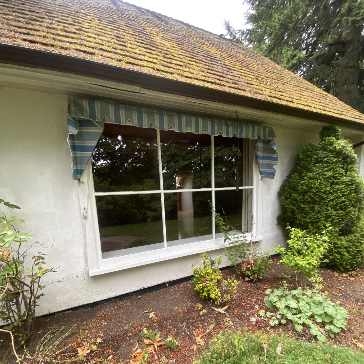 An older home from the exterior, with a very large window.