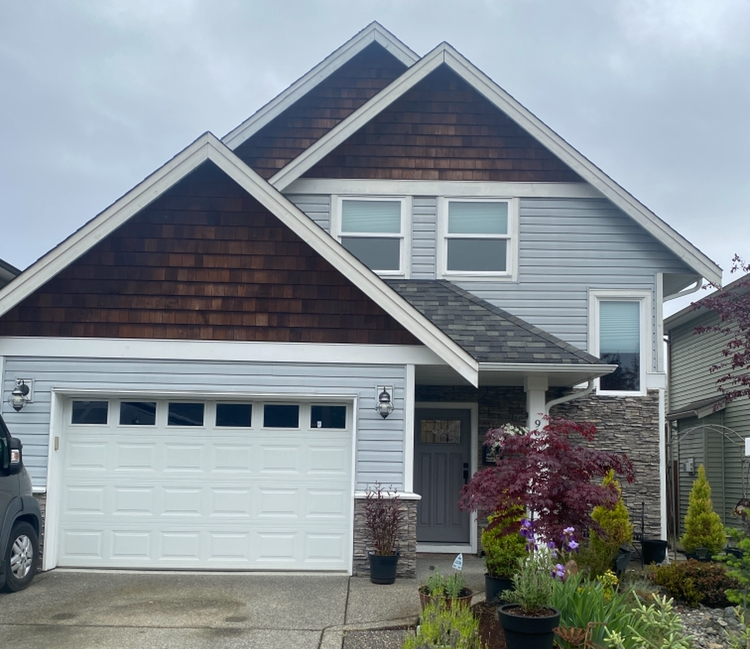 A grey house's exterior with cedar shake shingles and white trim.