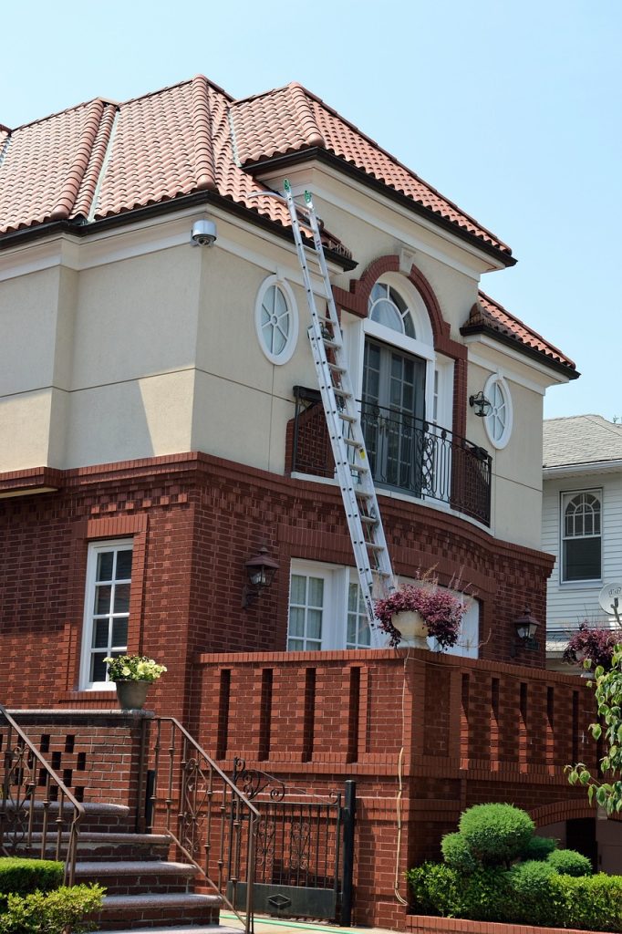 A very tall red and cream coloured house with a ladder leaning against the exterior.
