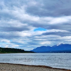 A pebbly beach in Crofton, BC with the ocean and mountains behind.
