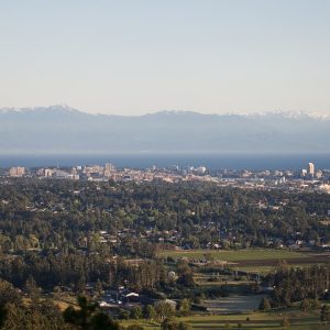 A city view of Saanich, with water and mountains behind.