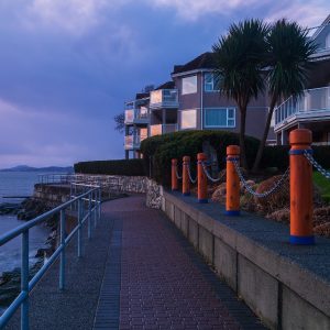 A view of the seawall by Sidney, BC at dusk with a few homes alongside the walkway.